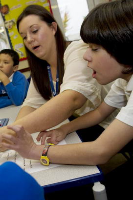 A teacher teaches a young boy
                  how to write