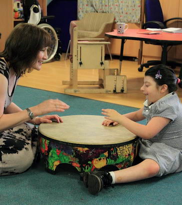 A girl and her teacher play a large drum