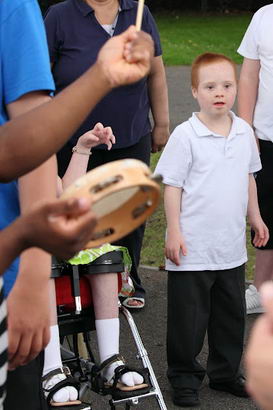 A young boy surrounded by friends, family
                  and musicians in a playground