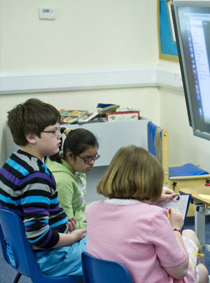 a group of children at various stages
                  of development sit in a circle with two of their teachers