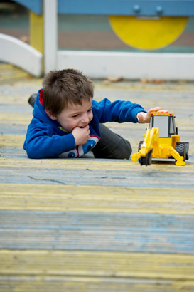 Boy on ground playing with digger
                  lorry