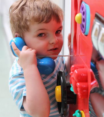 A young boy pretends to speak to someone
                  using a toy phone