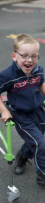 A young boy uses a walking frame
                  to move across a playground