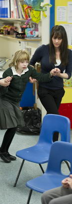 two teachers escort a young girl
                  back to her chair