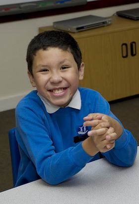 A young boy with his female teacher
                  smiles at the camera