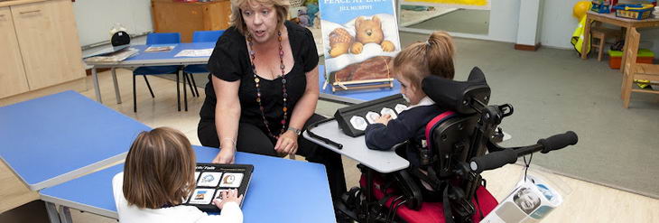 Two girls using tech talk with
                  a teacher]