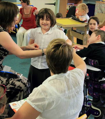 A girl stands, smiling, in a small group
                  of adults and children