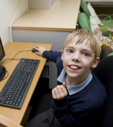 A boy sitting at a computer turns
                  and smiles