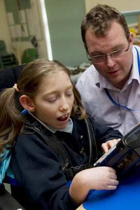 A girl uses a communication device
                  with her teacher