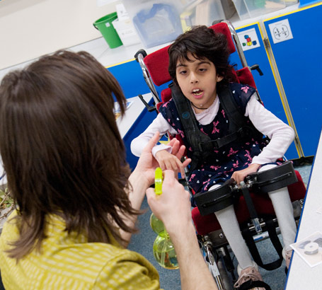 A girl in a specialist chair and
                  her teacher with a water spray