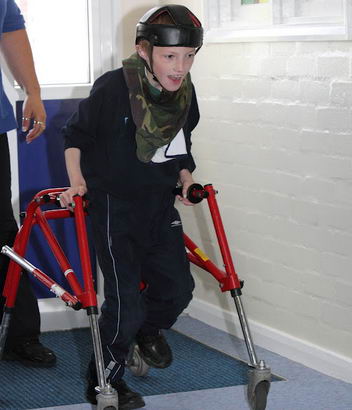 A young boy walks using a frame