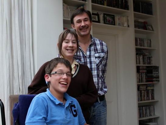 Daughter, father and son stand close in their
                  sitting room