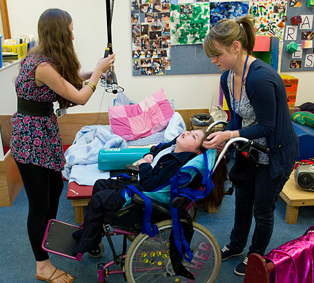 Child in wheelchair with two carers