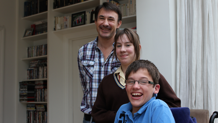 A portrait of a father and
                  his son and daughter smiling