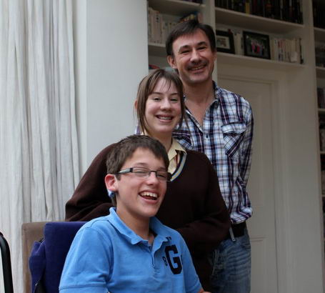Daughter, father and son stand close in their
                  sitting room