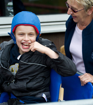 boy with protective helmet laughs
                  and smiles with his teacher