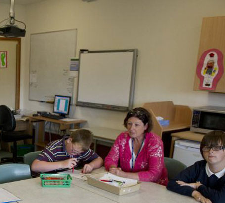 six pupils and two teachers sit in a circle