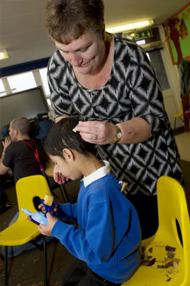 young boy with blue protective headgear
                  smiles at teacher