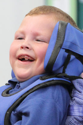 Teacher and boy in wheelchair smiling
                  at each other