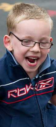 young boy in walking frame moves
                  from left to right across the frame smiling