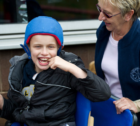 Child with padded headgear enjoys
                  a moment with his carer/teacher
