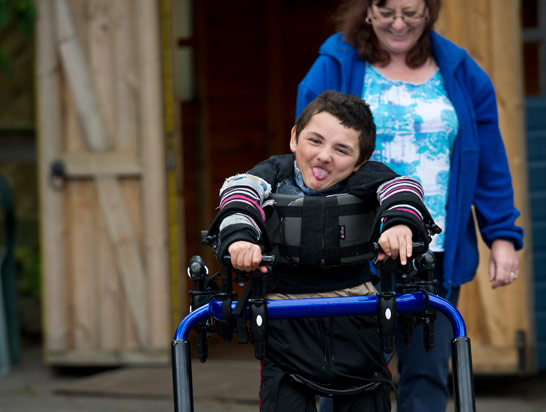 Boy in walking aid with carer