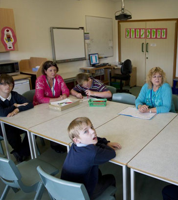 six pupils and two teachers sit in a circle