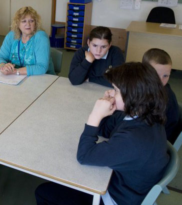 six pupils and two teachers sit in a circle