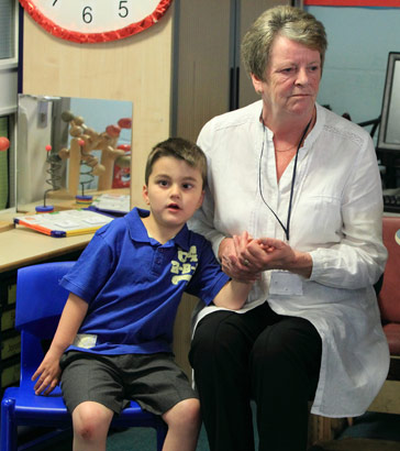 A carer holds a boy's hand
