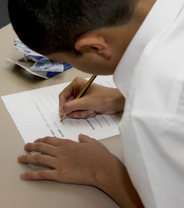 A boy writes on a piece of paper