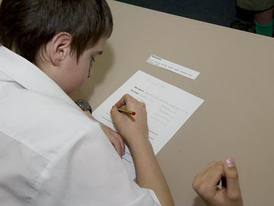 A boy writes on a piece of paper