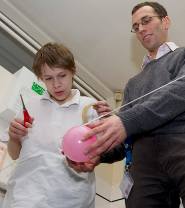 A science teacher and a boy prepare
                  a balloon rocket experiment