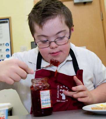 A boy prepares a jam sandwich