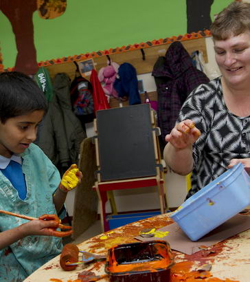 A boy painting with his teacher