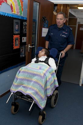 A boy covered in a blanket is
                  wheeled through a school corridor