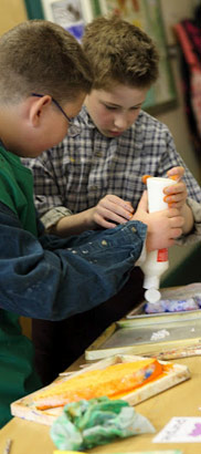 two boys putting paint on a palette 