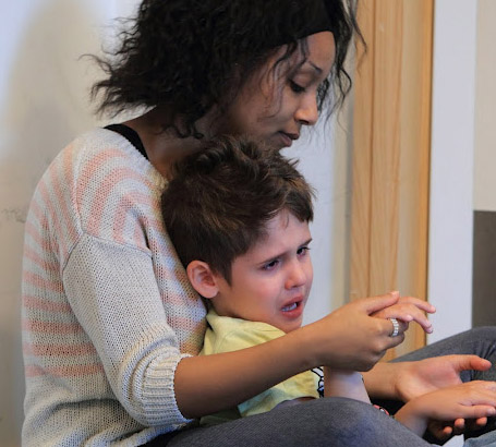 Carer comforting distressed boy