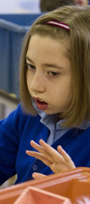 Teacher shows a small doll to a girl