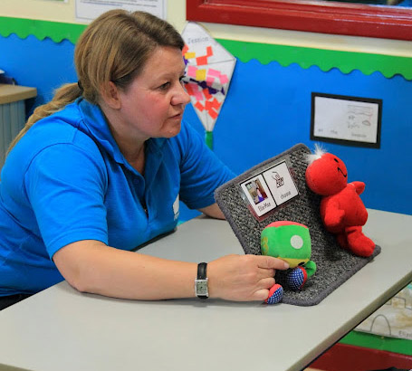 Teacher shows two objects to child.