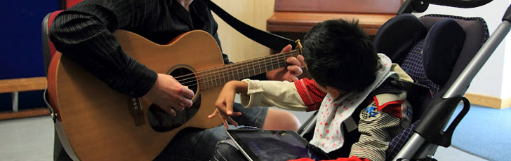 Disabled boy listening to guitar playing.