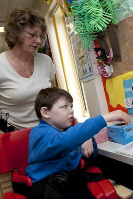 Boy in wheelchair fills in chart
                  on wall