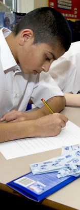 Three teenage boys take part in
                  a more traditional learning setting – taking a formal test in their classroom