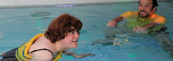 A teenage girl and a male teacher use
                  intensive interaction techniques in a swimming pool