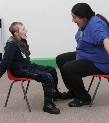 A female teacher uses Intensive Interaction
                  techniques with a young boy