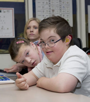 A girl wearing head protection looks at
                  some cards laid out by a teacher