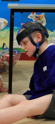 A boy looks at several objects presented
                  to him by a teacher