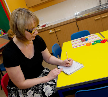 A teacher writes on a notebook