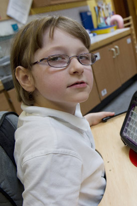 A girl with a communication device
                  turns to look at the camera