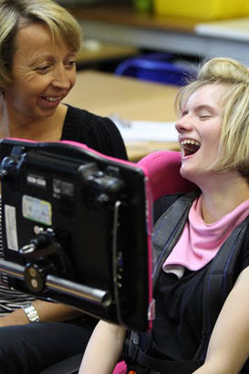 Pupil and teacher share a joke in front
                  of AAC screen