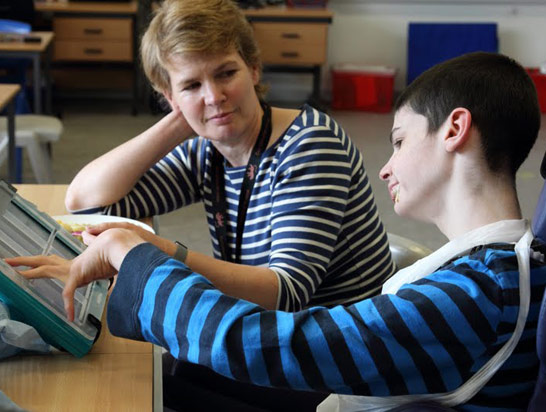 Teenager and teacher use AAC screen over
                  meal